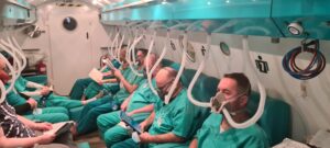 grupa ludzi podłaczona do komory hiperbarycznej
